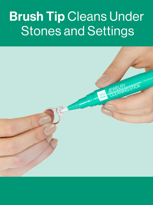 Hands using the Gem Glow Jewelry Cleaning Stick to clean in-between settings on a diamond ring.