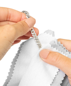 Hands cleaning a silver bracelet with a Gold & Silver Polishing Cloth