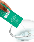 Hand pouring Jewelry Cleaner Packet into a glass bowl containing jewelry