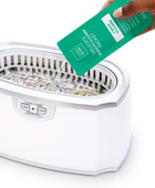 Hand pouring Jewelry Cleaner Packet into a CLEAEN+CARE Ultrasonic Machine