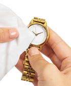 Hands cleaning a gold watch with a Jewelry & Watch Cleansing Wipe towelette
