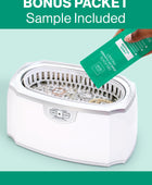 A hand pouring the bonus GEM GLOW cleaner packet sample into the Ultrasonic Jewelry Cleaner basin with jewelry submerged.