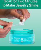 Hands using the included touch-up brush to clean a pearl ring after soaking in the GEM GLOW 7.5 oz. Delicate Jewelry Cleaner.