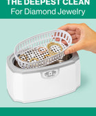 A hand placing the included basket full of jewelry into the GEM GLOW Ultrasonic Cleaner for a thorough cleaning.